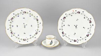 deux assiettes et une tasse posées sur un support, sur une surface grise
