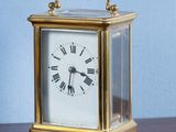 une petite horloge posée sur une table en bois, avec un mur bleu en arrière-plan