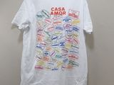 white t - shirt with a bunch of stickers on it hanging on a hanger