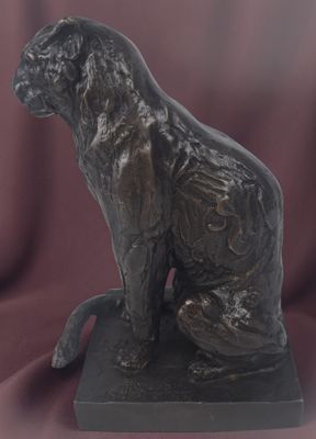 bronze statue of a cat sitting on a base on a red cloth