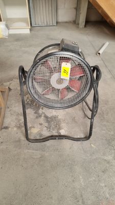 a fan that is sitting on a stand in a garage