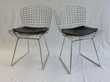 pair of chrome wire chairs with black leather seat pads