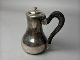 une cafetière en argent avec une anse, posée sur une table