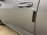 the door handle of a silver car with a sticker on it