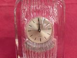 a clear glass clock with a black face on a red background