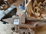 une grande enclume métallique posée sur un bloc de bois