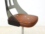 a chair that has a brown seat on a metal stand