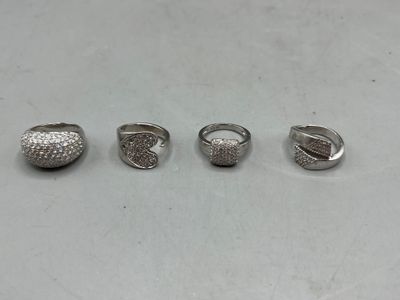 quatre bagues en argent posées sur une table avec un fond blanc
