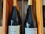 several bottles of wine are lined up on a wooden shelf
