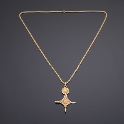 un collier en or avec un pendentif en forme de croix sur une chaîne