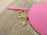 a pink purse with a gold keychain on it