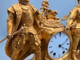 a gold clock with a man and a woman on top of it