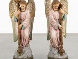 two figurines of angels are standing on a marble base