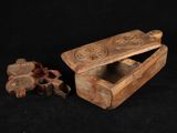 une vieille boîte en bois munie d'une poignée et contenant un petit morceau de bois