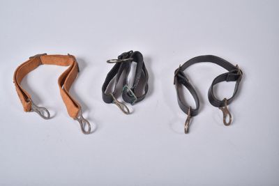 trois types différents de laisses pour chien en cuir posées sur une surface blanche