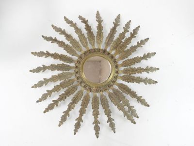 a gold sunburst on a white surface with a mirror
