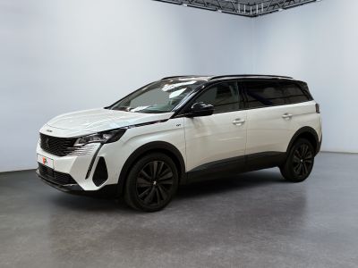 Un SUV blanc est garé dans une grande pièce aux murs blancs.