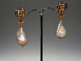 a pair of pearl and gold earrings on a stand
