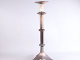 un grand bougeoir en métal surmonté d'une bougie
