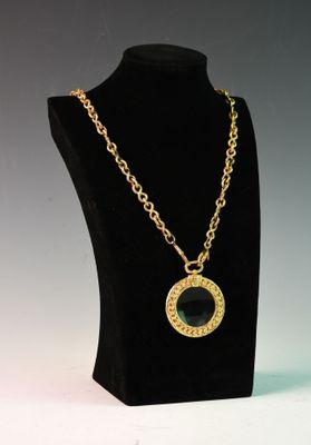 un collier noir et doré avec un pendentif en forme de cercle sur un mannequin