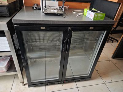 un réfrigérateur à porte vitrée posé sur un plan de travail dans une cuisine