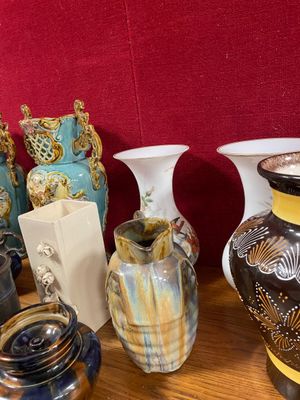 de nombreux vases posés sur une table, avec un mur rouge en arrière-plan