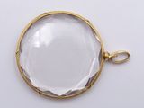 a close up of a gold plated pendant with a clear glass face