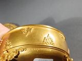 someone is holding a gold plate with a gold decoration on it