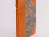 an orange book sitting on top of a white table next to a white wall
