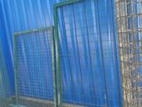 a blue wall behind the fence and a yellow ball in front of it