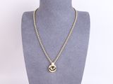 a gold necklace with a circular pendant on a mannequin neck