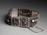 a close up of a silver bracelet with a chain around it