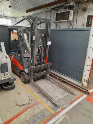 a fork lift truck parked in a warehouse with a truck in the background