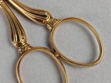 a pair of gold scissors on a white surface