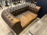 brown leather couch in a restaurant with tables and chairs in the background