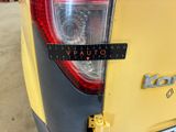 the rear end of a yellow car with a sticker on it