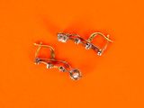 pair of earrings on an orange surface with a small bead in the middle
