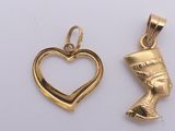 two gold pendants with a heart and an egyptian head