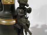 a black vase with a statue of a boy sitting on top of it