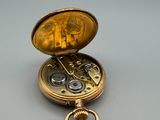 a gold pocket watch sitting on a table with a key