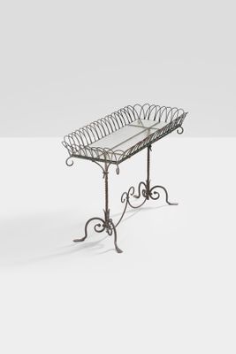 an iron table with a glass top on a white surface