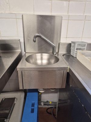 a sink in the middle of a kitchen with a blue trash can underneath it