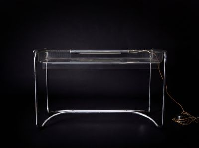 bureau en plexiglas transparent sur lequel sont posés un clavier et une souris