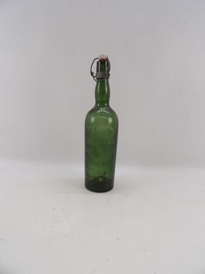 une vieille bouteille en verre vert posée sur une table blanche