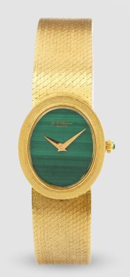 une image montrant un gros plan d'une montre-bracelet en or avec un cadran vert