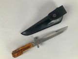 two knives and a knife sheath on a white surface