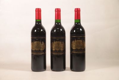 trois bouteilles de vin rouge posées l'une à côté de l'autre sur une surface blanche