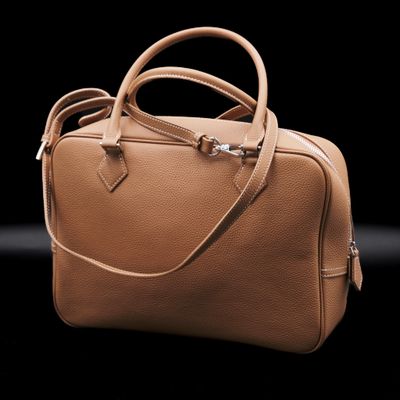 tan leather handbag on a black background with a black background