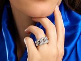 close up of a woman in a blue shirt with a diamond ring on her finger