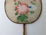a fan with a painting of flowers and a butterfly on it